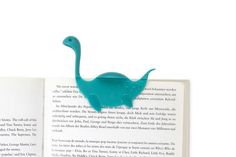 an open book with a teal plastic dinosaur on it