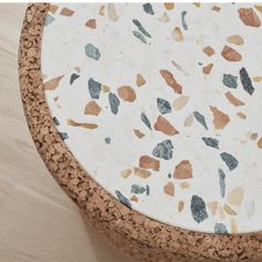 a close up of a cork table top on a wooden floor with white and brown speckles