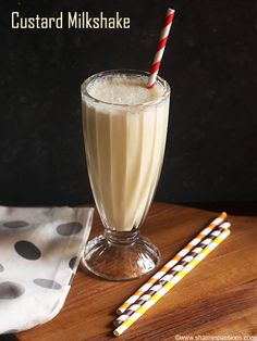 a glass filled with milk sitting on top of a table next to two straws