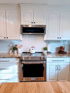 a kitchen with white cabinets and stainless steel stove top oven in the center, surrounded by wood flooring