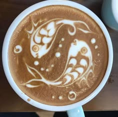 a cappuccino with an intricate design in the foam on it's surface