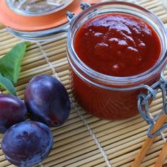 plums sit next to a jar of jam on a bamboo mat