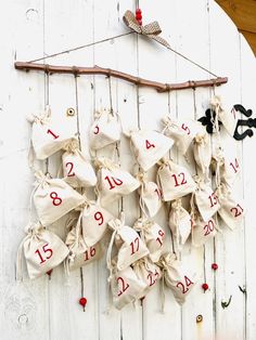 a bunch of bags hanging on the side of a white wall with numbers and hooks