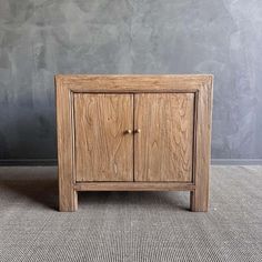 a wooden cabinet sitting on top of a carpeted floor next to a gray wall