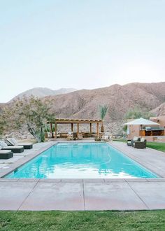 an empty swimming pool in the middle of a desert area with mountains in the background