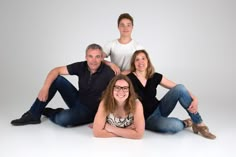 a family posing for a photo in front of a white background with their arms around each other