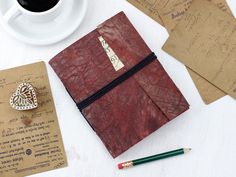 a notepad and pen are sitting on a table next to an envelope with a heart shaped stamp