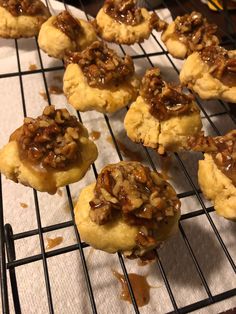 several cookies are cooling on a rack with caramel sauce and pecans in the background