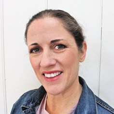 a woman wearing a denim jacket smiling at the camera