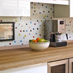 a bowl of fruit sitting on top of a kitchen counter next to a coffee maker