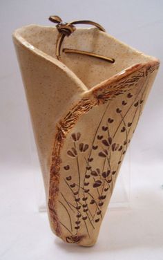 the vase is made out of clay and has brown flowers on it's sides