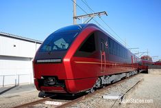 a red train traveling past a white building