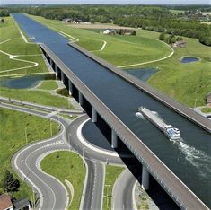 an aerial view of a bridge over a river with a boat on the water below