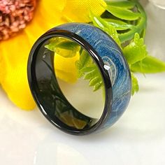 a black and blue ring sitting on top of a white table next to yellow flowers