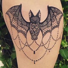 a bat tattoo on the back of a woman's leg