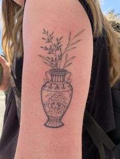 a woman with a tattoo on her arm that has a vase with flowers in it