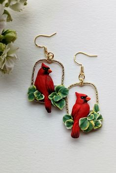 a pair of red birds sitting on top of green leaves next to a white flower