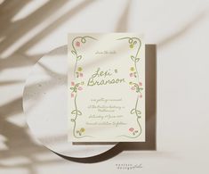 a wedding card on top of a plate next to the shadow of a palm tree