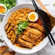 a bowl filled with noodles and meat next to chopsticks on top of a table