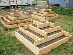 several wooden raised garden beds with plants growing out of them in the middle of a yard