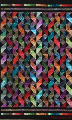 a quilt made with many different colors and shapes, including black fabric on the bottom