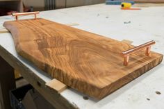 a wooden cutting board sitting on top of a table next to a pair of scissors