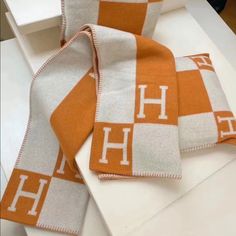 two orange and white towels sitting on top of a counter next to each other with the letter h on them