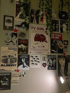 there are many posters on the wall and one is lit up with a lamp next to it