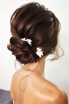 a woman with brown hair and white flowers in her hair is looking back at the camera