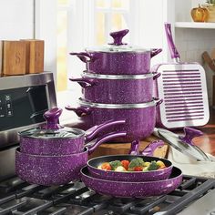 purple pots and pans are stacked on top of each other in front of an oven