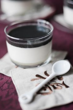 a spoon sitting on top of a napkin next to a glass of milk and two cups