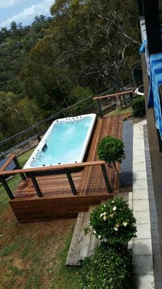 an above ground hot tub in the middle of a decked area next to a swimming pool