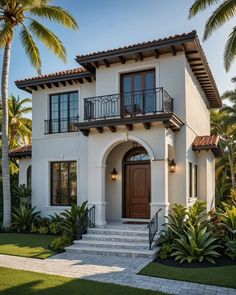 a white two story house with palm trees in the front yard and stairs leading up to it