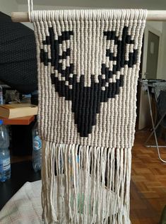 a woven wall hanging with black and white designs on it's side in a living room