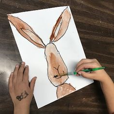 a child's hand drawing a bunny on paper