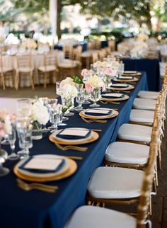 a long table is set with blue linens and gold chargers