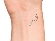 a small tattoo on the wrist of a woman's arm, with a bird drawn on it