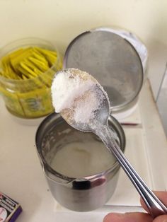 a spoon full of sugar sitting on top of a metal container filled with yellow sticks