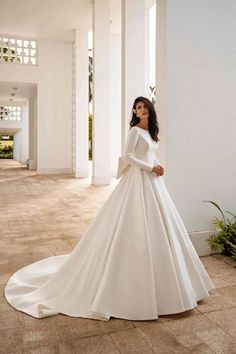 a woman in a white wedding dress standing on the floor with her arms behind her back