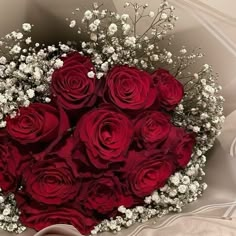 a bouquet of red roses and baby's breath in a heart - shaped arrangement