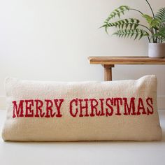 a christmas pillow sitting on top of a table next to a potted plant