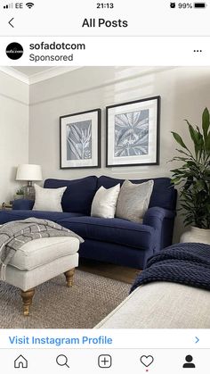 a living room with blue couches and white pillows on the floor, two framed pictures above them