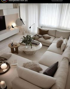 a living room filled with lots of white furniture and candles in front of a window