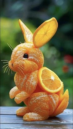 an orange stuffed animal sitting on top of a wooden table next to sliced oranges