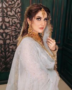 a woman in a white sari and gold jewelry