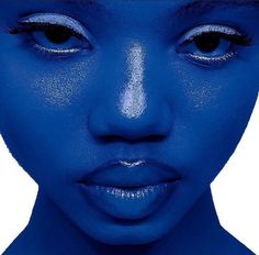 a woman's face is covered in blue powder and has her eyes painted bright