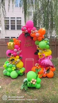 an outdoor birthday decoration with balloons and decorations on the grass in front of a house