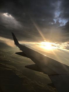 an airplane wing with the sun shining through clouds