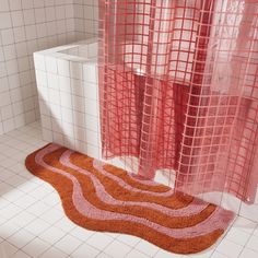 a bathroom with a red rug on the floor next to a toilet and shower curtain