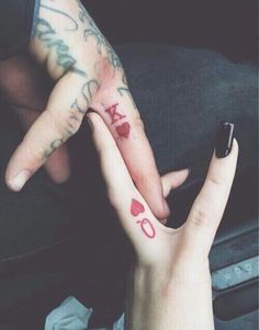 two people with tattoos on their fingers holding each other's hands and one has the word love written on it